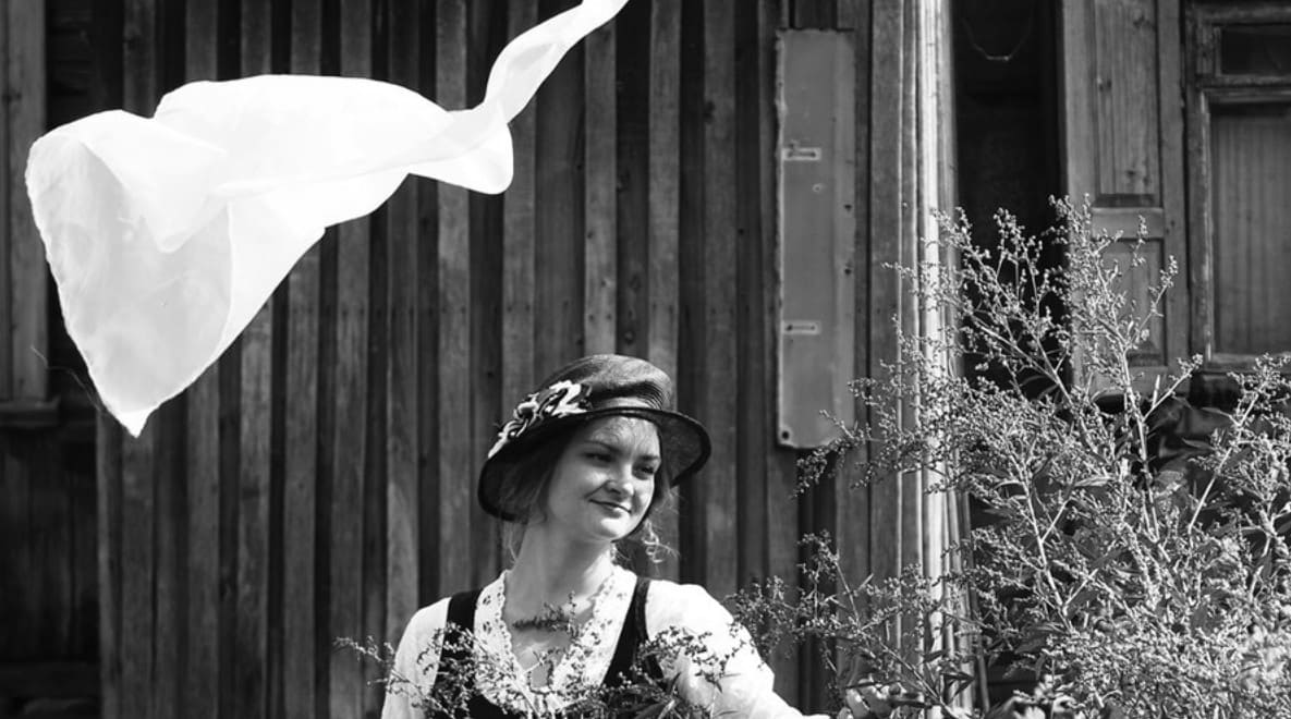 Girl admiring flowers and a piece of thin fabric flying over her head